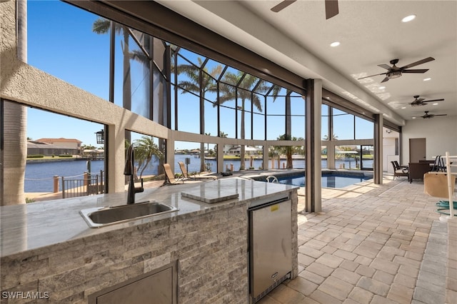 603 SW 53rd Ter, Cape Coral, FL 33914 - view of patio / terrace with a sink, area for grilling, an outdoor pool, ceiling fan, and a water view