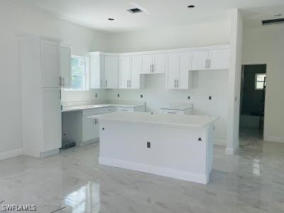 1237 Cloplon St E, Lehigh Acres, FL 33974 - kitchen featuring a center island, white cabinets, and baseboards