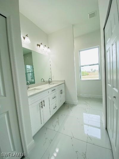 1237 Cloplon St E, Lehigh Acres, FL 33974 - bathroom with marble look tile flooring, baseboards, and double vanity