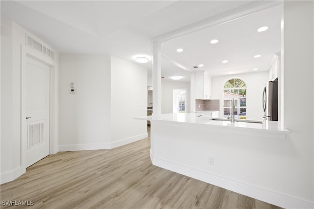 505 Mardel Dr Unit 106, Naples, FL 34104 - kitchen featuring freestanding refrigerator, white cabinetry, light countertops, light wood finished floors, and baseboards