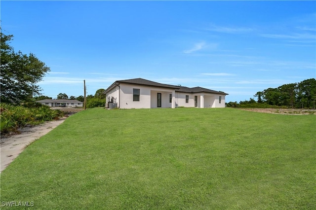 4646 Leonard Blvd S, Lehigh Acres, FL 33973 - rear view of house with a lawn, stucco siding, and central air condition unit