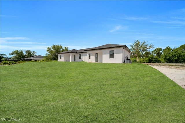 4646 Leonard Blvd S, Lehigh Acres, FL 33973 - rear view of property featuring a yard, stucco siding, and central air condition unit