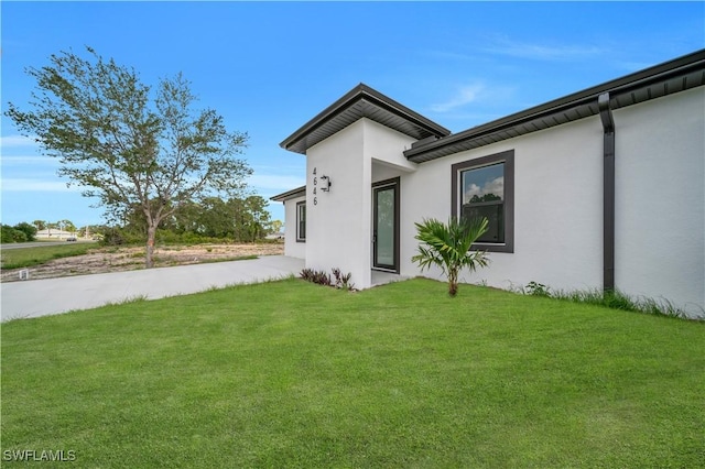 4646 Leonard Blvd S, Lehigh Acres, FL 33973 - rear view of house featuring stucco siding and a yard