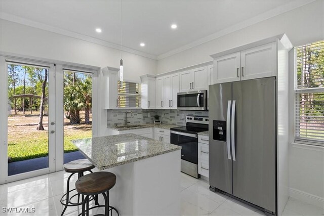 2948 2nd Ave NE, Naples, FL 34120 - kitchen with stainless steel appliances, a sink, backsplash, a center island, and white cabinetry