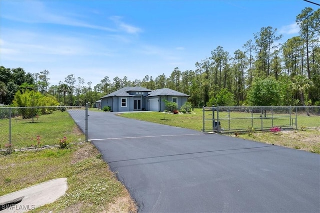 2948 2nd Ave NE, Naples, FL 34120 - view of front of house featuring a gate, asphalt driveway, a garage, and view of wooded area