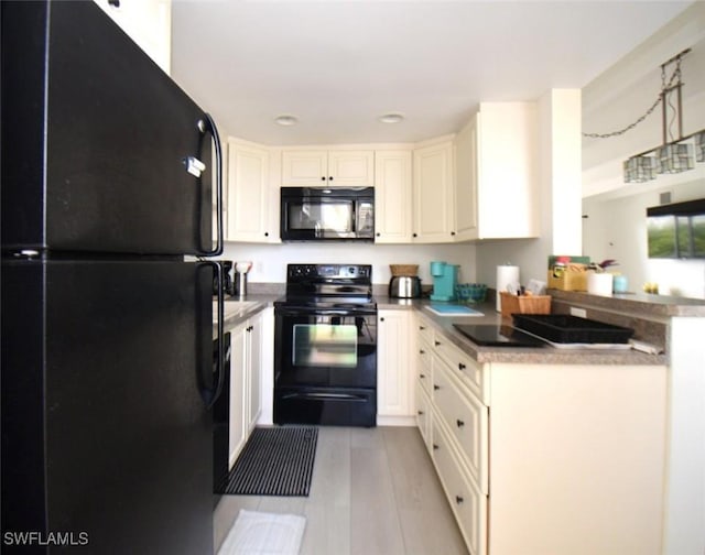 kitchen featuring white cabinets, a peninsula, and black appliances