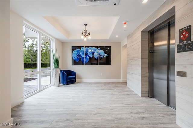 spare room featuring a chandelier, elevator, visible vents, and wood finished floors