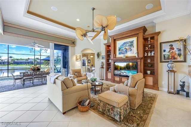 8993 Crooked Stick Ct, Naples, FL 34113 - living room featuring arched walkways, a ceiling fan, light tile patterned floors, a tray ceiling, and ornamental molding