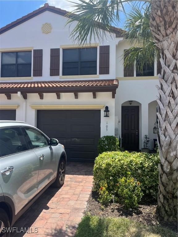 9453 Montebello Way Unit 103, Fort Myers, FL 33908 - view of front facade featuring an attached garage, stucco siding, a tile roof, and driveway