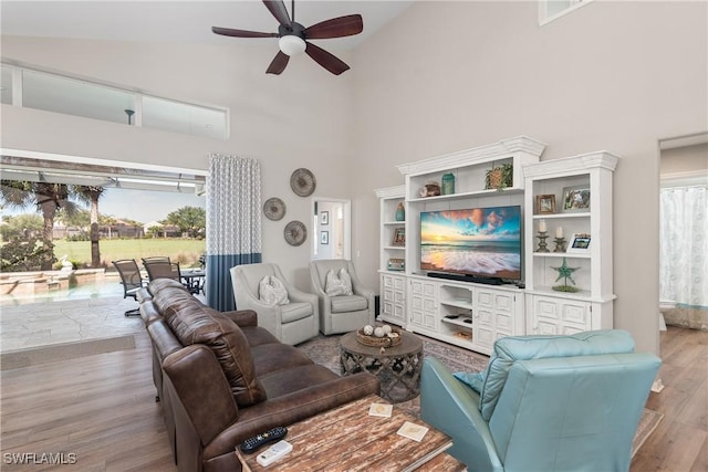 living area featuring a ceiling fan, wood finished floors, and high vaulted ceiling