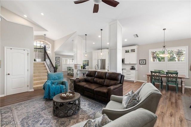 living area with ceiling fan, a wealth of natural light, light wood-style floors, and stairs