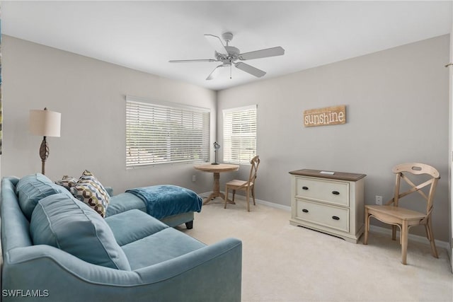 living area with baseboards, light colored carpet, and ceiling fan