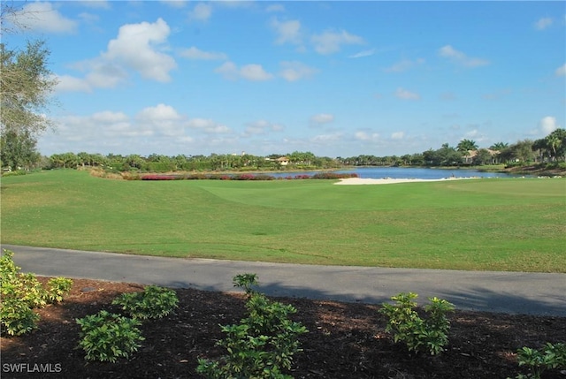 surrounding community with a lawn, view of golf course, and a water view
