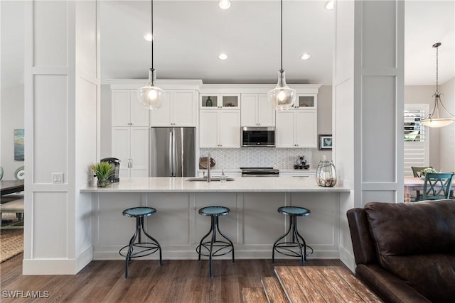 kitchen with a peninsula, glass insert cabinets, stainless steel appliances, and a sink