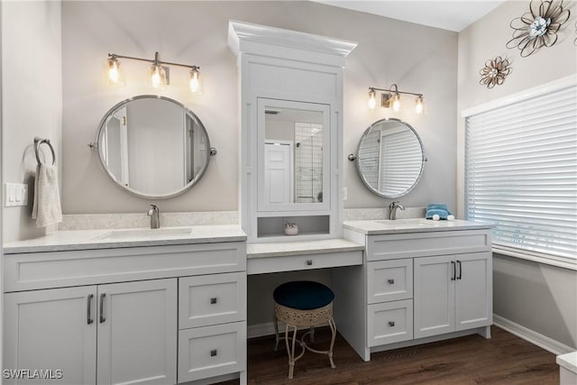 bathroom with two vanities, wood finished floors, baseboards, and a sink