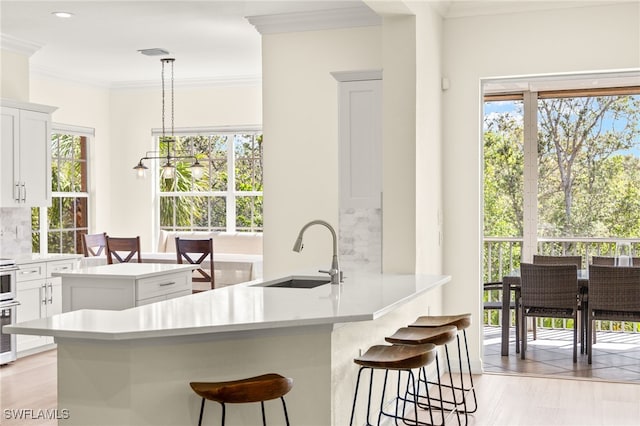 kitchen with a sink, white cabinetry, a breakfast bar, and ornamental molding