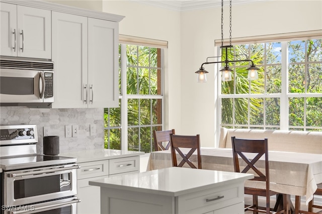 kitchen with backsplash, light countertops, ornamental molding, stainless steel appliances, and white cabinetry