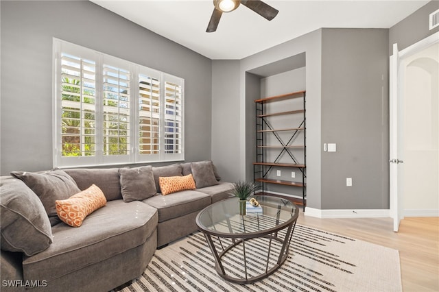 living area with light wood-style floors, a ceiling fan, baseboards, and visible vents