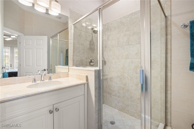 ensuite bathroom featuring vanity, connected bathroom, ceiling fan, and a stall shower