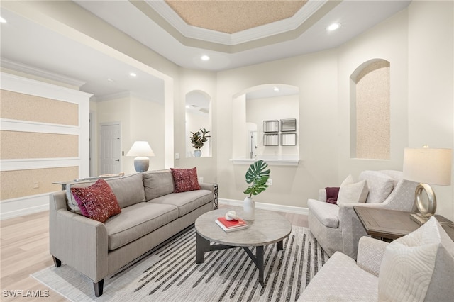 living room with crown molding, a raised ceiling, recessed lighting, and light wood-type flooring
