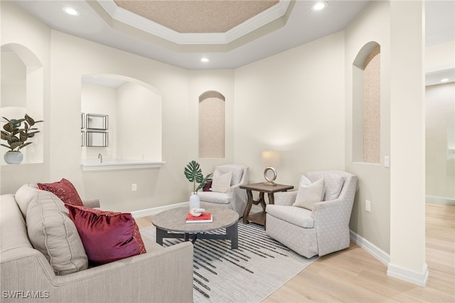 living area with recessed lighting, a tray ceiling, ornamental molding, and wood finished floors