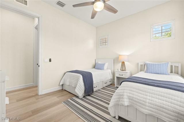 bedroom featuring baseboards, visible vents, ceiling fan, and light wood finished floors