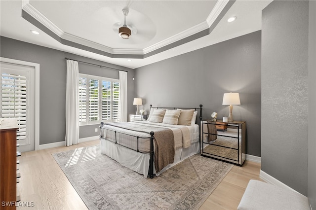 bedroom featuring light wood-type flooring, ornamental molding, a tray ceiling, and recessed lighting