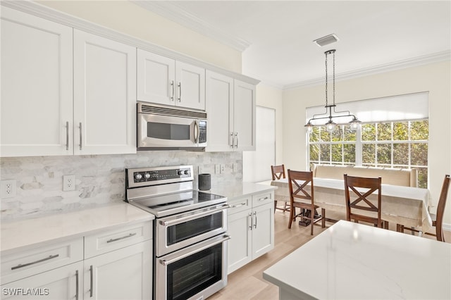kitchen with crown molding, decorative backsplash, white cabinetry, and stainless steel appliances