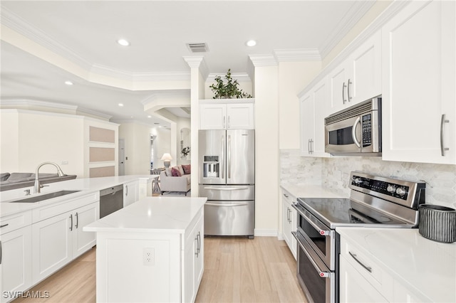 kitchen with visible vents, a center island, a sink, white cabinets, and stainless steel appliances