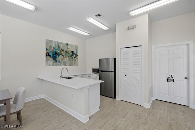 kitchen with a sink, light countertops, stainless steel appliances, a peninsula, and visible vents