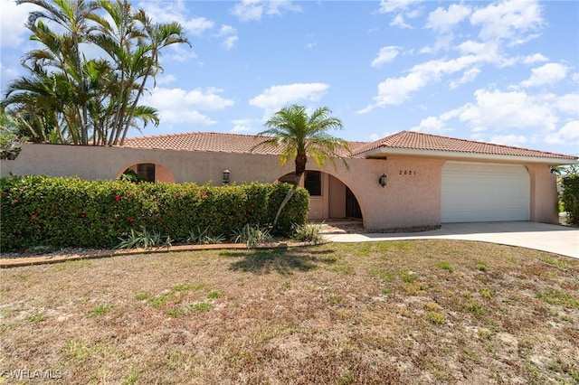 view of front of property with an attached garage, a tile roof, concrete driveway, and stucco siding