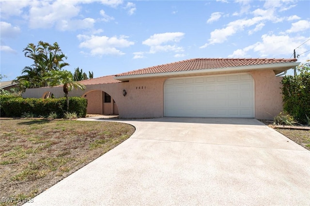 view of front facade featuring stucco siding, a tile roof, concrete driveway, and a garage