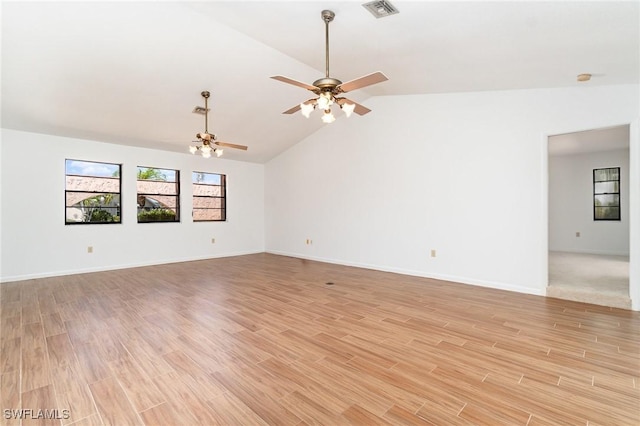 spare room featuring baseboards, visible vents, light wood-style floors, lofted ceiling, and ceiling fan with notable chandelier