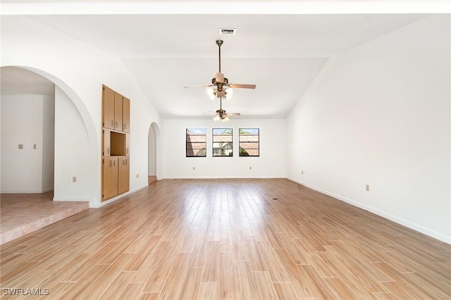 unfurnished living room featuring vaulted ceiling, arched walkways, light wood-style floors, and a ceiling fan