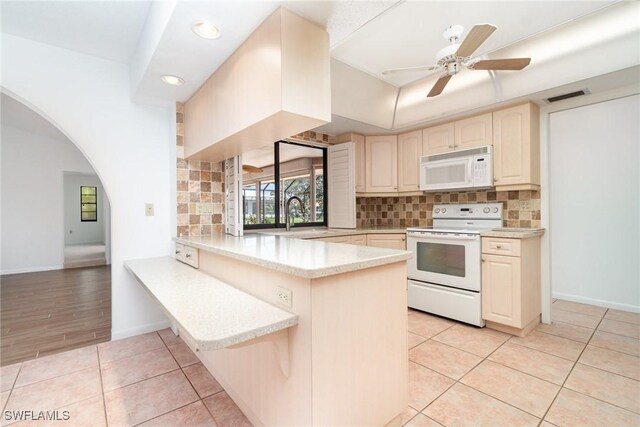 kitchen with a peninsula, visible vents, backsplash, white appliances, and light countertops