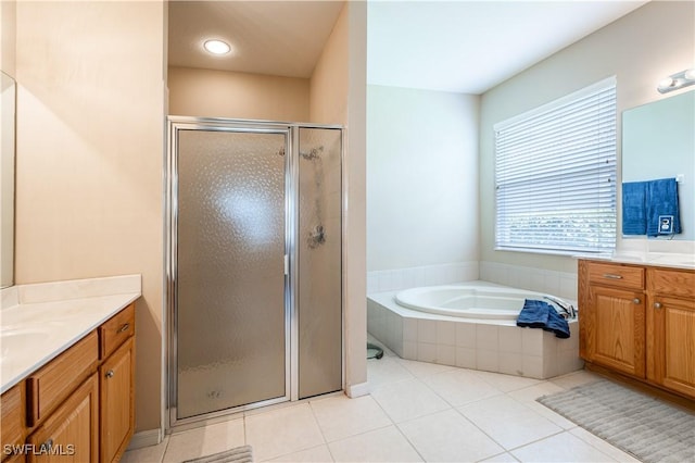 bathroom with tile patterned flooring, a shower stall, a garden tub, and two vanities