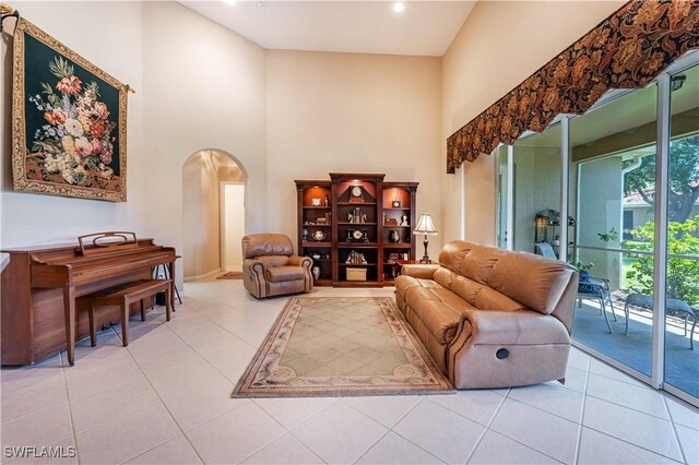 living area featuring arched walkways, tile patterned floors, recessed lighting, and a towering ceiling