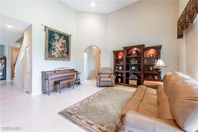 living room with baseboards, a high ceiling, recessed lighting, arched walkways, and light tile patterned floors