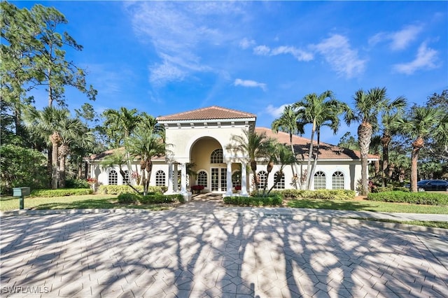 mediterranean / spanish home with stucco siding, french doors, and a tile roof