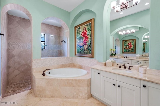 full bath with an inviting chandelier, a walk in shower, a garden tub, and vanity