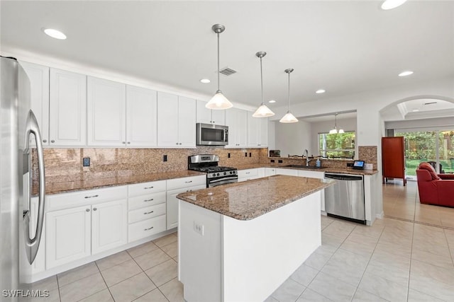 9046 Astonia Way, Estero, FL 33967 - kitchen with white cabinets, stainless steel appliances, backsplash, light tile patterned floors, and arched walkways