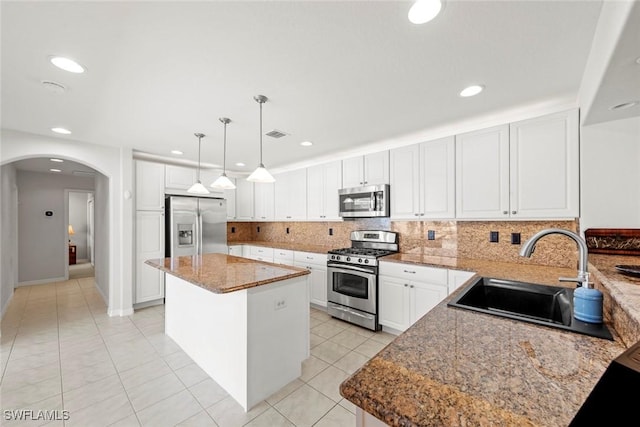 9046 Astonia Way, Estero, FL 33967 - kitchen with a sink, arched walkways, a kitchen island, tasteful backsplash, and appliances with stainless steel finishes