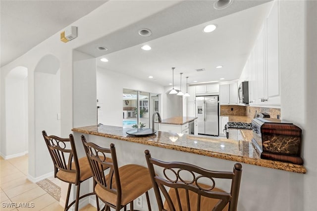 9046 Astonia Way, Estero, FL 33967 - kitchen with white cabinets, stainless steel appliances, a peninsula, recessed lighting, and light stone countertops