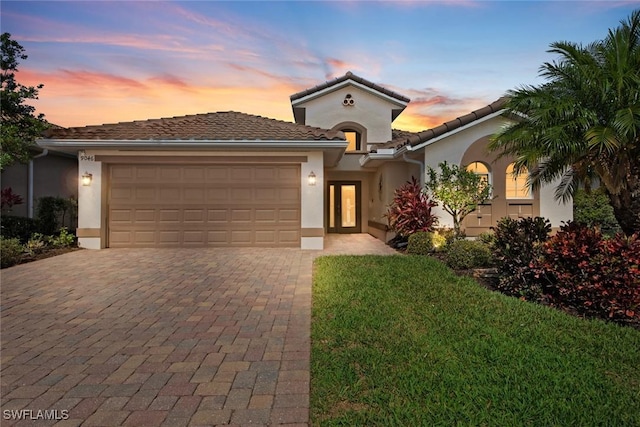 9046 Astonia Way, Estero, FL 33967 - mediterranean / spanish house featuring a garage, a front lawn, stucco siding, and decorative driveway