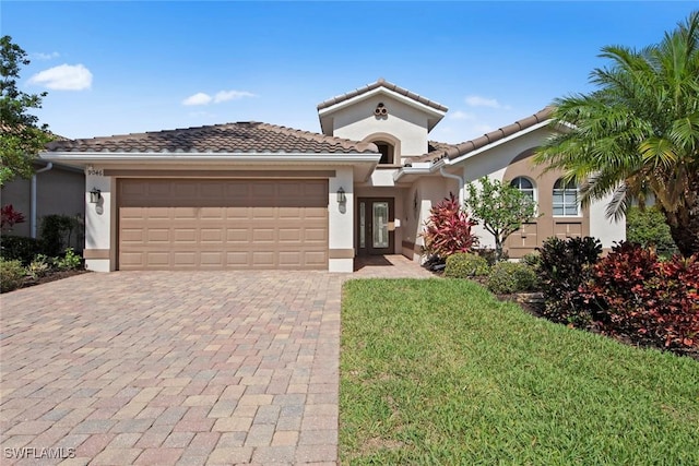9046 Astonia Way, Estero, FL 33967 - mediterranean / spanish home featuring a tile roof, decorative driveway, a front lawn, an attached garage, and stucco siding
