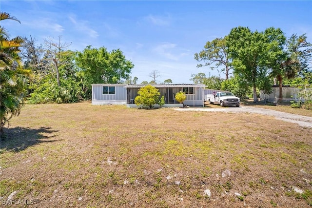 manufactured / mobile home with driveway, fence, a front yard, and a sunroom