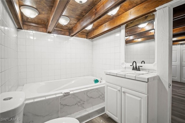 full bath featuring a tub with marble appearance, tile walls, beam ceiling, vanity, and wood finished floors