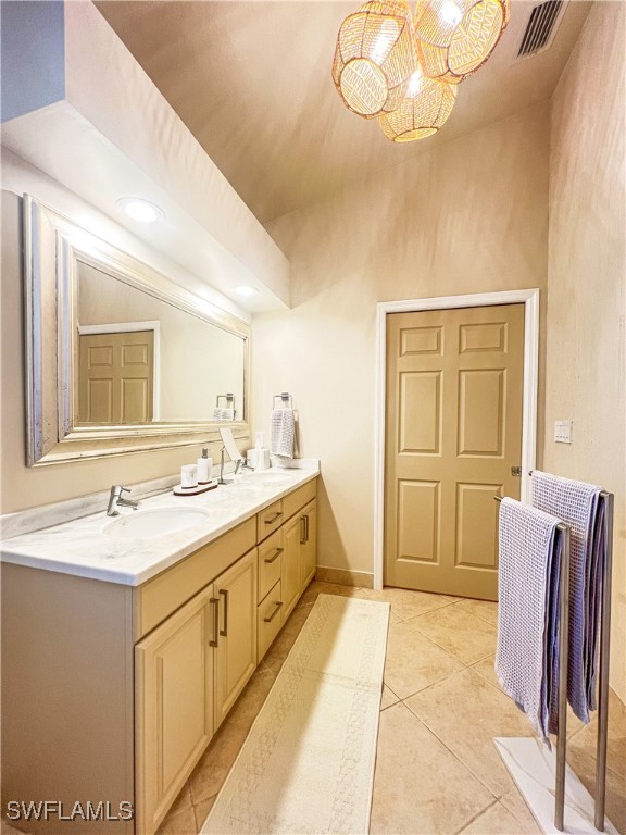 full bath featuring tile patterned floors, double vanity, visible vents, a sink, and a notable chandelier
