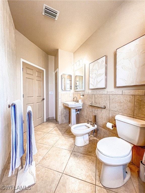 bathroom featuring tile patterned floors, toilet, tile walls, visible vents, and a bidet