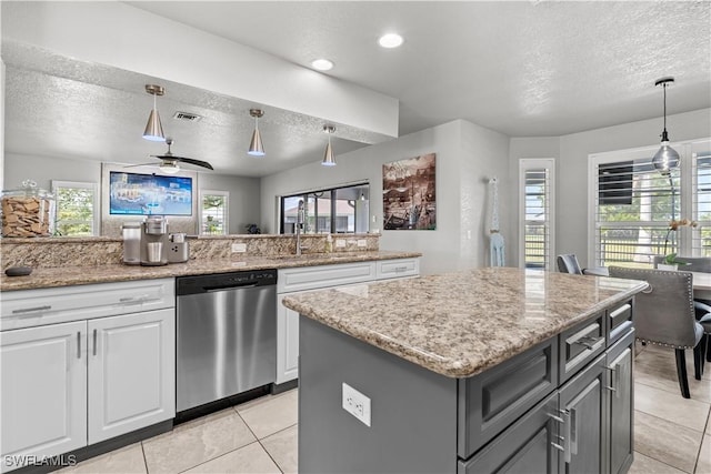 kitchen with a textured ceiling, stainless steel dishwasher, white cabinetry, and a sink